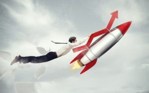Business person holding onto an rocket in flight to illustrate increased productivity.