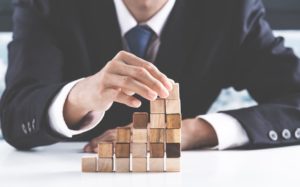 Business person stacking blocks to illustrate financial structure.