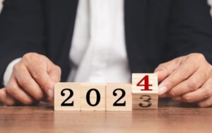 Business person turning blocks from showing 2023 to 2024 to illustrate a blog post about business trends 2024.
