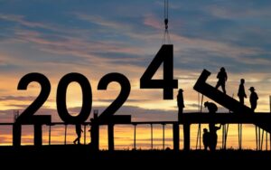 Construction workers in the sunset, working on a structure that spells out 2024 to illustrate a blog post on 2024 employment law issues.