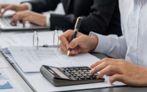 People examining documents and crunching numbers to illustrate deal structuring.