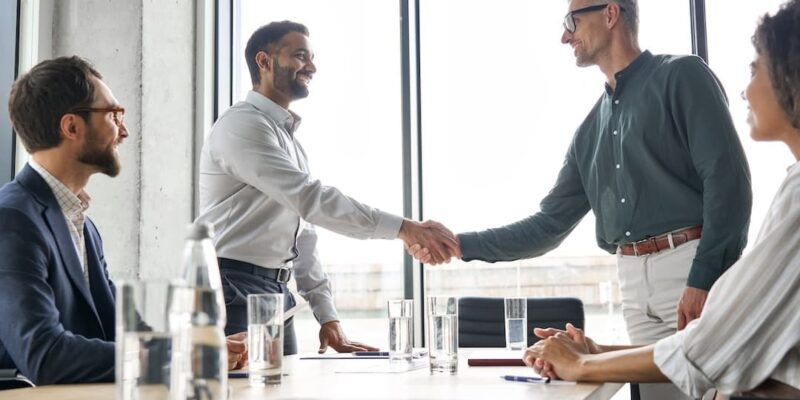 Professionals shaking hands to illustrate a blog post discussing how to hire fractional CFO services for SaaS companies.
