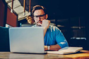 Business owner frowning at their computer to illustrate a blog post about how to improve cash flow.
